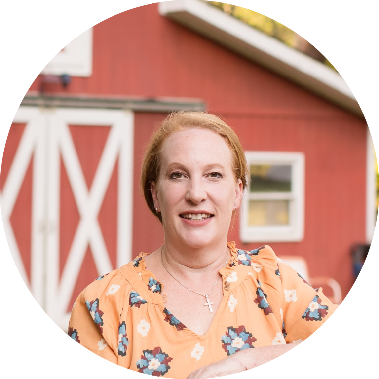 imgi_28_Rosero-250-1-modified Person smiling in front of a red barn with a cross necklace.