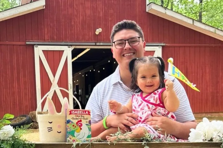 Man and child sitting by a barn with Easter decorations and a personalized book.